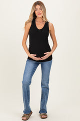 woman wearing a black ribbed maternity tank top and holding her baby bump, paired with light blue flared jeans