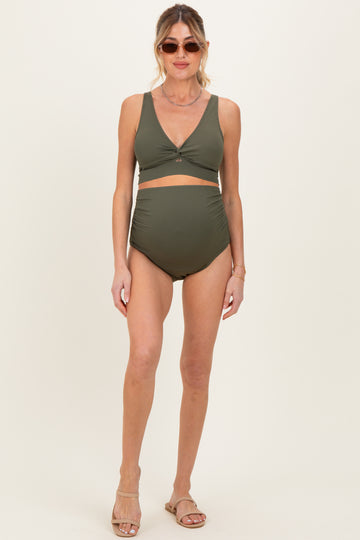 woman wearing an olive green ribbed maternity bikini with a twist front top and high-waisted bottom, showing her baby bump