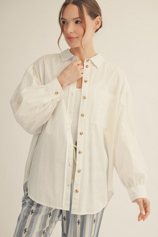 woman wearing an oversized white button-up shirt with puff sleeves and a chest pocket, styled with striped pants