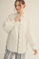 woman wearing an oversized white button-up shirt with puff sleeves and a chest pocket, styled with striped pants