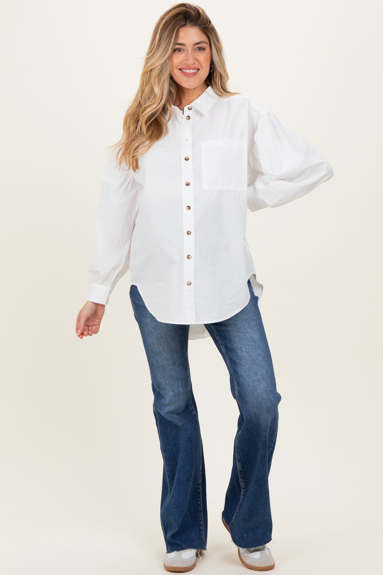 woman wearing a white button-up maternity shirt with balloon sleeves and blue flared jeans