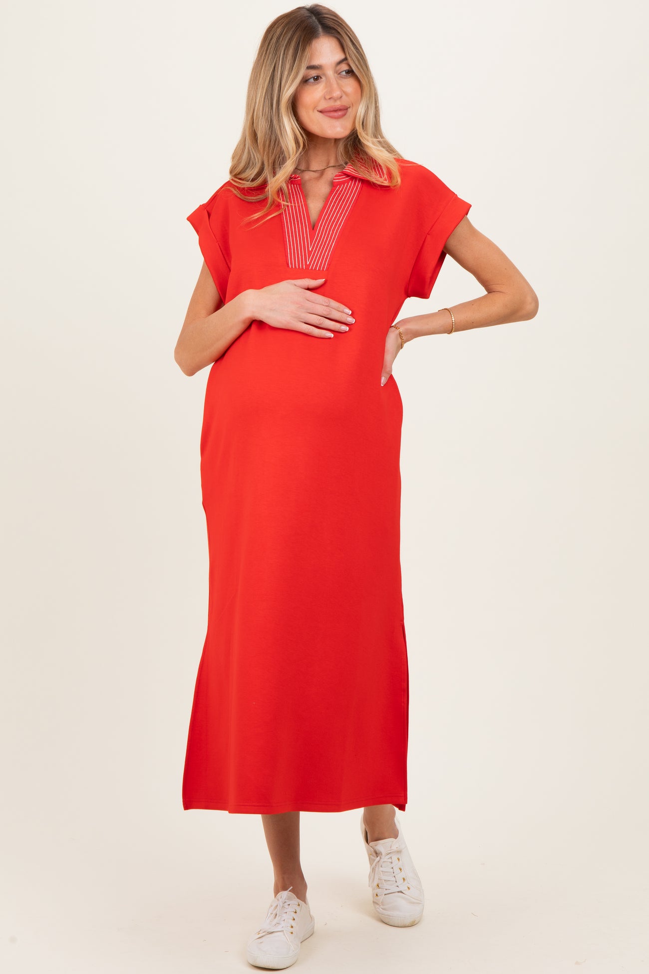 woman wearing a red maternity dress with a v-neck and short sleeves, holding her baby bump