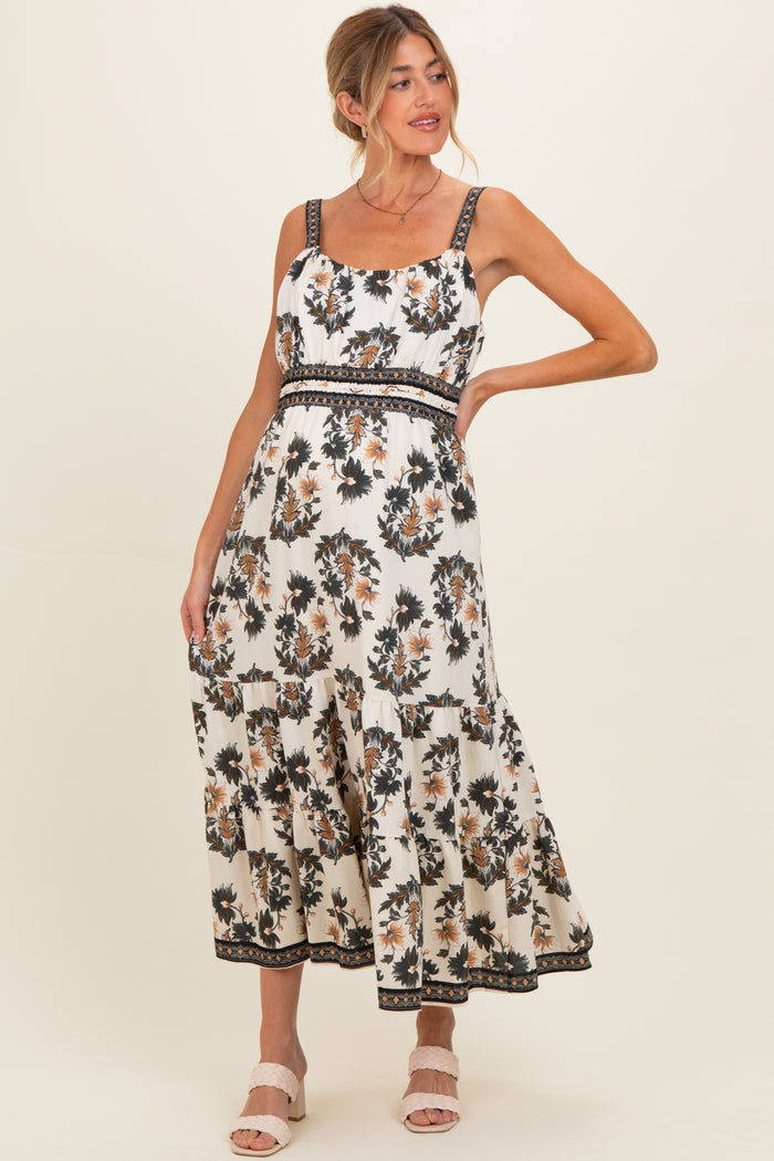 woman wearing a floral print maternity maxi dress with a fitted bodice and tiered skirt, showing her baby bump