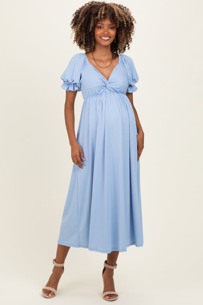 woman wearing a light blue striped maternity dress with short puff sleeves and a tie front, showing her baby bump