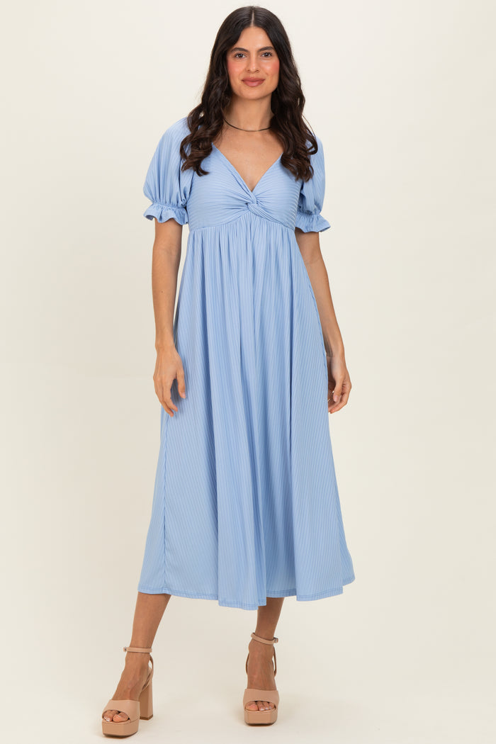 woman wearing a light blue, puff sleeve maxi dress with a twist front detail and a flowy silhouette