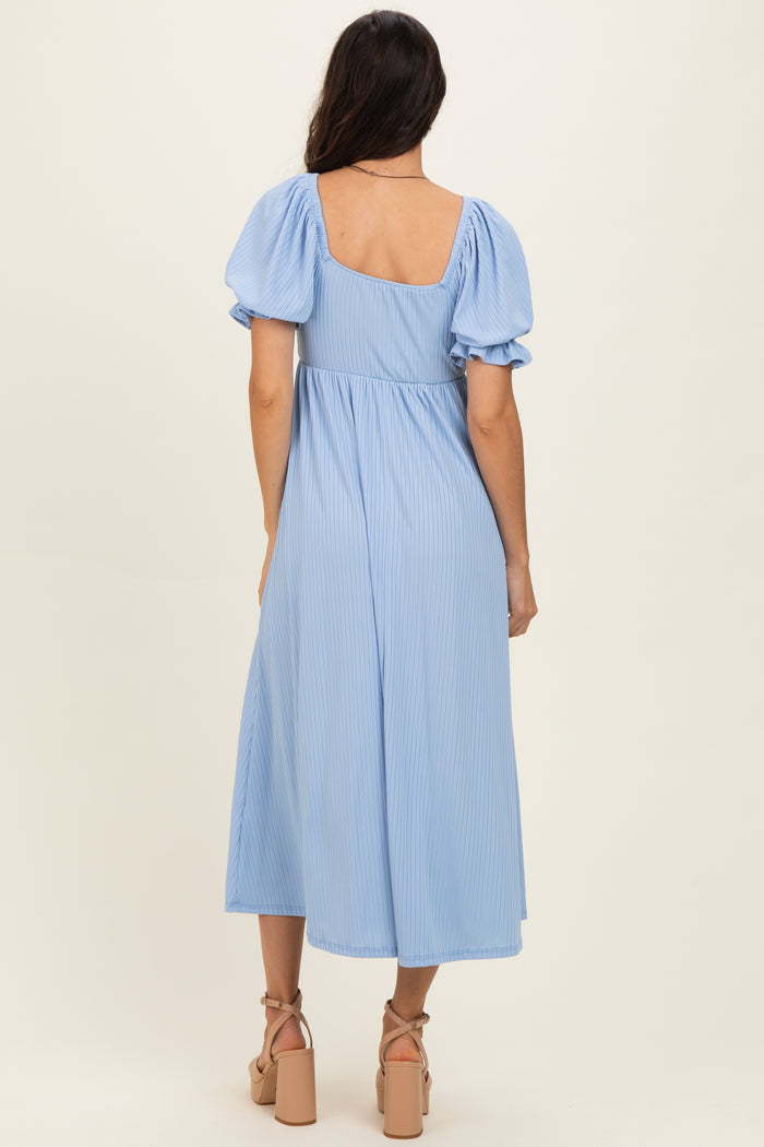 woman wearing a light blue midi dress with puff sleeves and a square back, standing in profile