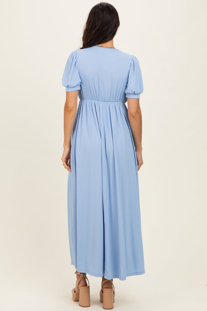 woman wearing a light blue pleated maxi dress with short puff sleeves and a fitted waist from the back