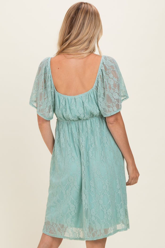 woman wearing a backless light teal lace dress with short sleeves and a fitted waist