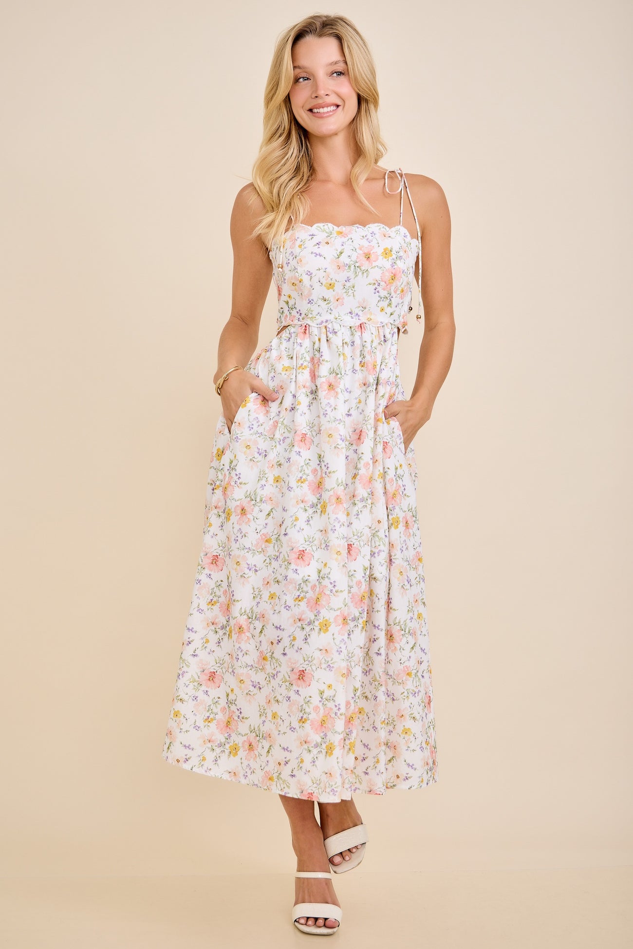 woman wearing a white floral maxi dress with adjustable straps and pockets