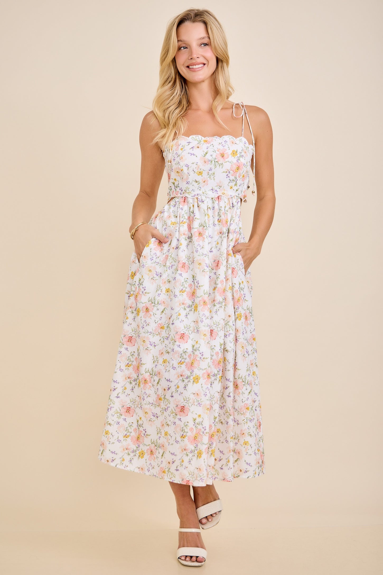 woman wearing a white floral maxi dress with adjustable straps and pockets