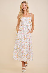 woman wearing a white floral maxi dress with adjustable straps and pockets