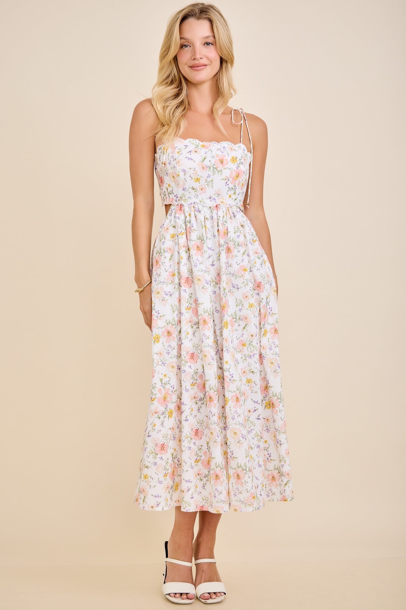 woman wearing a floral print midi dress with adjustable straps and a cinched waist