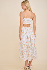 woman wearing a white floral crop top and matching maxi skirt with tied shoulder straps and a gathered back