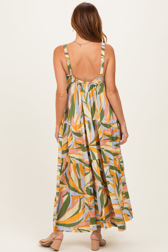 woman wearing a colorful leafy maxi dress with a backless design and flowing skirt