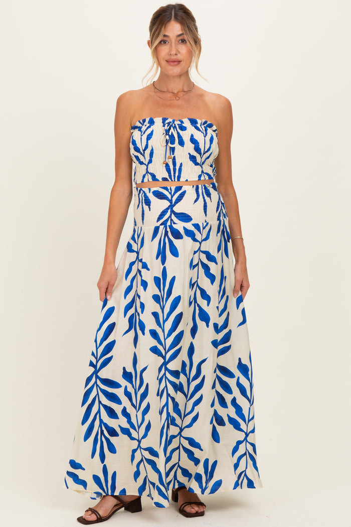 woman wearing a maternity two-piece set with a strapless crop top and a long skirt featuring a blue leaf print