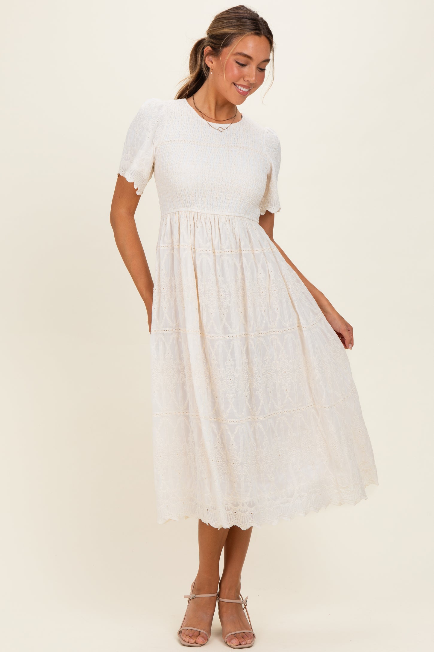 woman wearing a cream puff sleeve midi dress with a lace skirt and pockets, standing elegantly with a slight smile