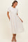 woman wearing a cream puff sleeve midi dress with a lace skirt and pockets, standing elegantly with a slight smile