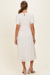 woman wearing a white midi dress with short sleeves and a smocked bodice, showing a keyhole back detail