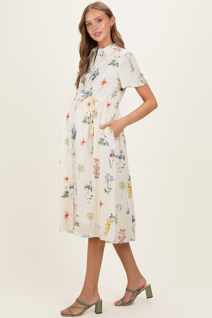 woman wearing a floral short sleeve maternity dress with pockets and a tie waist, showcasing her baby bump