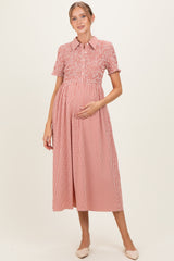 woman wearing a red and white gingham maternity dress with a collared neckline and short sleeves, holding her baby bump