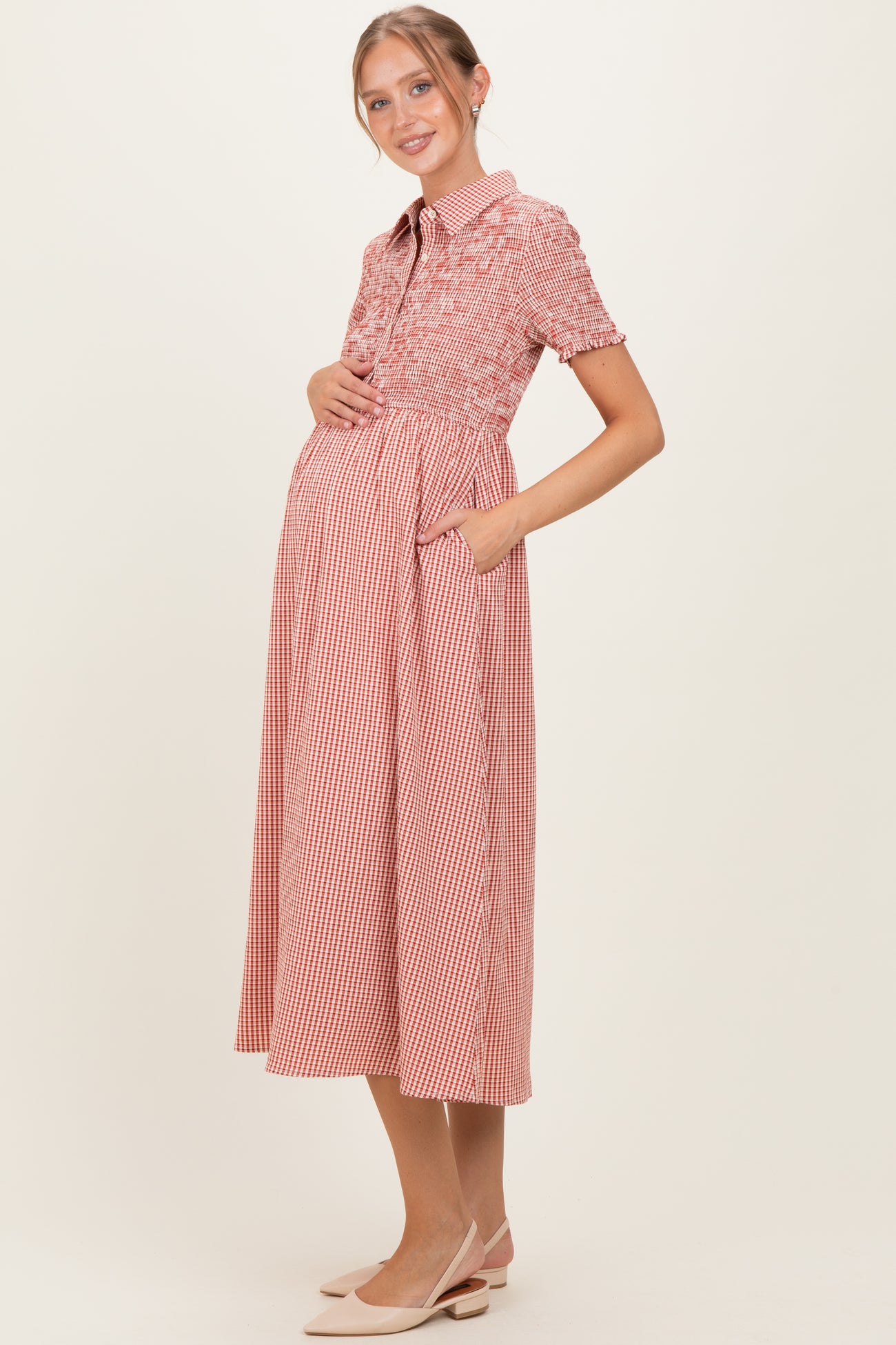 woman wearing a red and white gingham maternity dress with short sleeves and a button-up collar, showing her baby bump