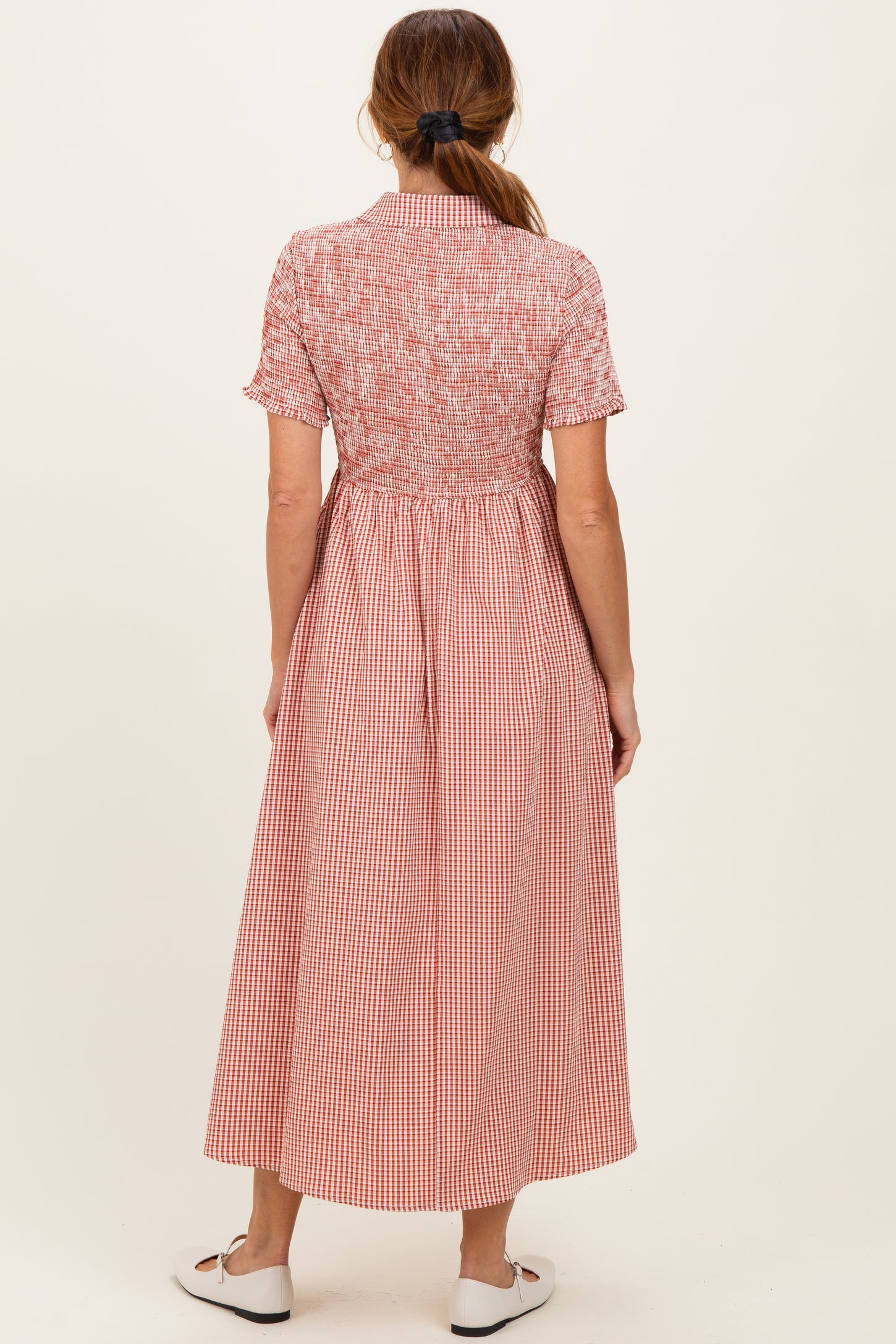 woman wearing a red and white gingham midi dress with short sleeves and a fitted bodice, seen from the back