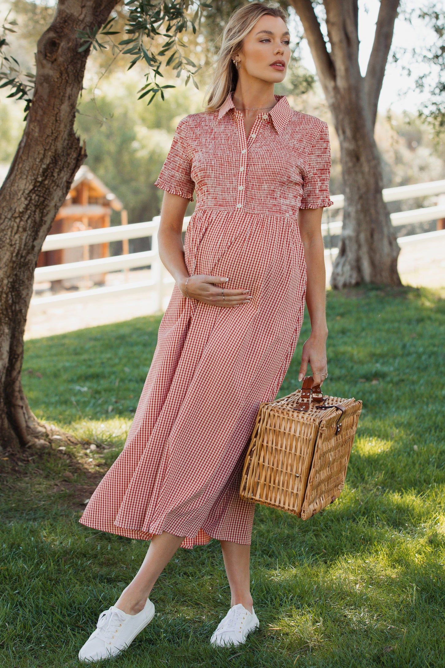 woman wearing a red and white gingham maternity dress with short sleeves, holding a basket and showing her baby bump