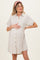 woman wearing a beige short sleeve maternity dress with button details and holding her baby bump