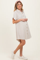 woman wearing a beige collared button-up maternity dress with a visible baby bump and a pink headband