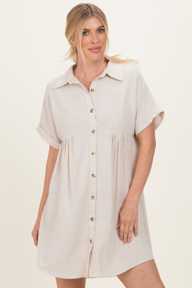 woman wearing a beige short sleeve button-up shirt dress with a relaxed fit and rolled sleeves