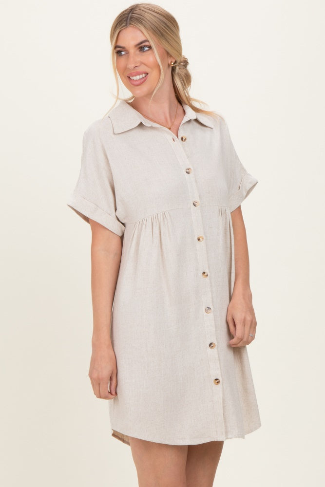 woman wearing a beige short sleeve button-up shirt dress with a gathered waist and rolled sleeves