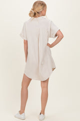 woman wearing a short sleeve beige linen shirt dress with a relaxed fit and rolled sleeves, seen from the back