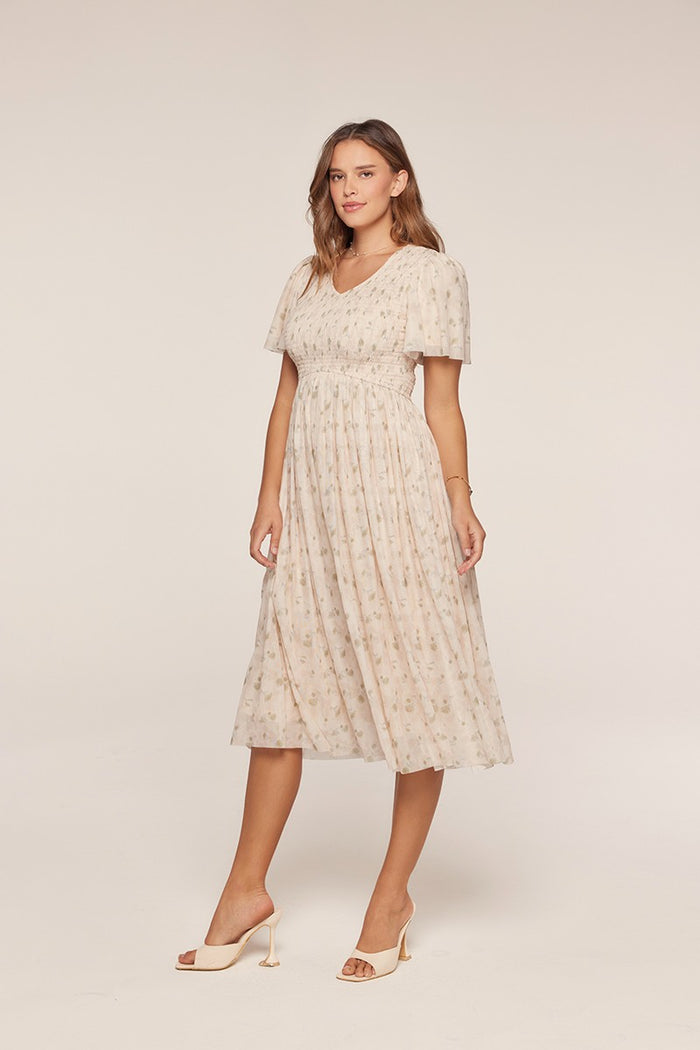 woman wearing a light beige floral midi dress with short puff sleeves and a fitted waist