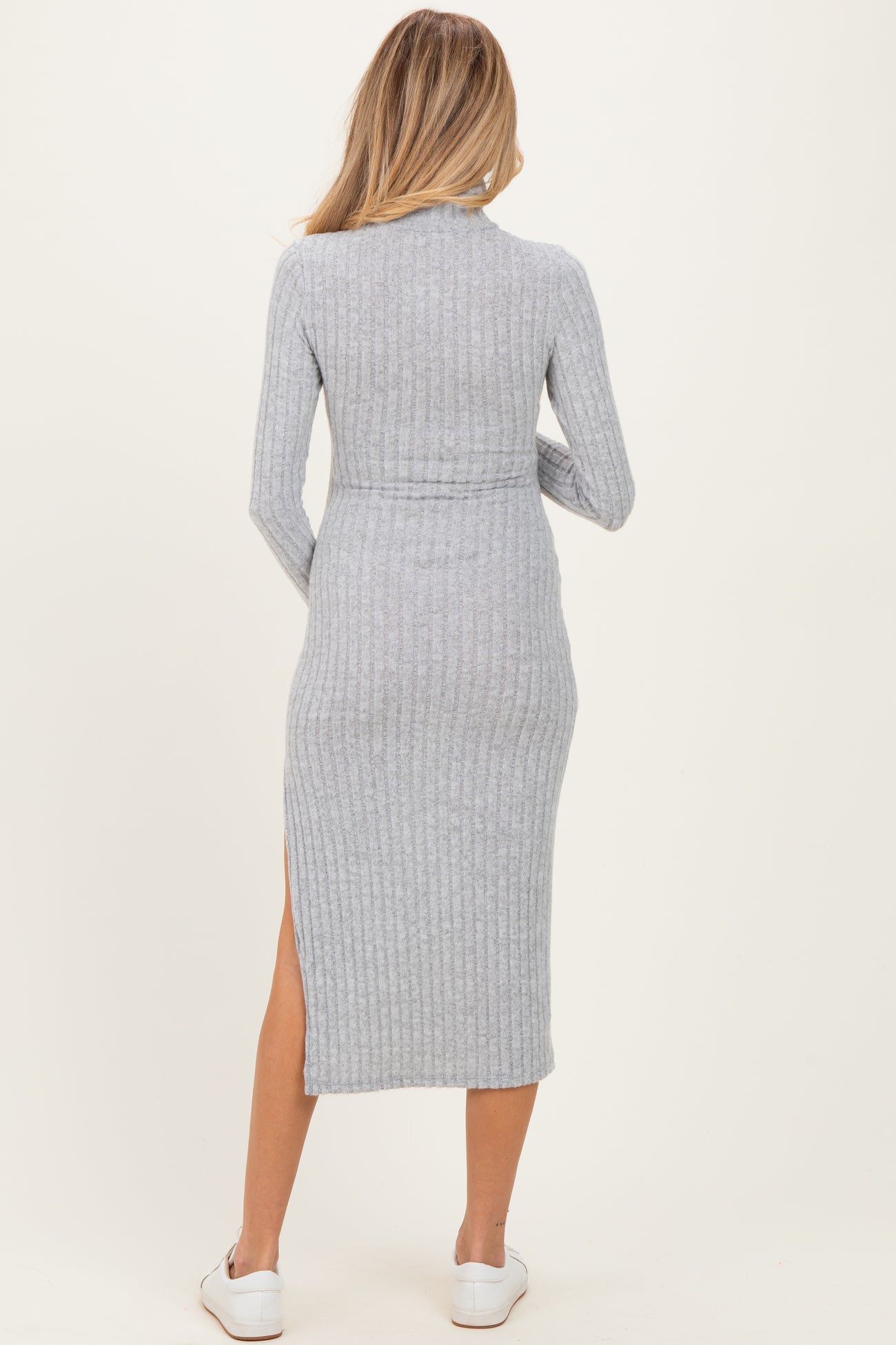 woman wearing a grey ribbed long sleeve maternity dress with a side slit, viewed from the back