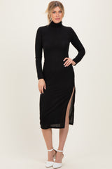 woman wearing a black ribbed midi dress with long sleeves and a side slit, standing on a neutral background