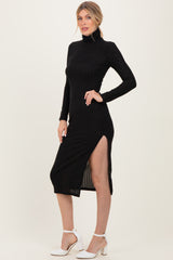 woman wearing a black ribbed knit midi dress with a turtleneck and side slit, styled with white high heels