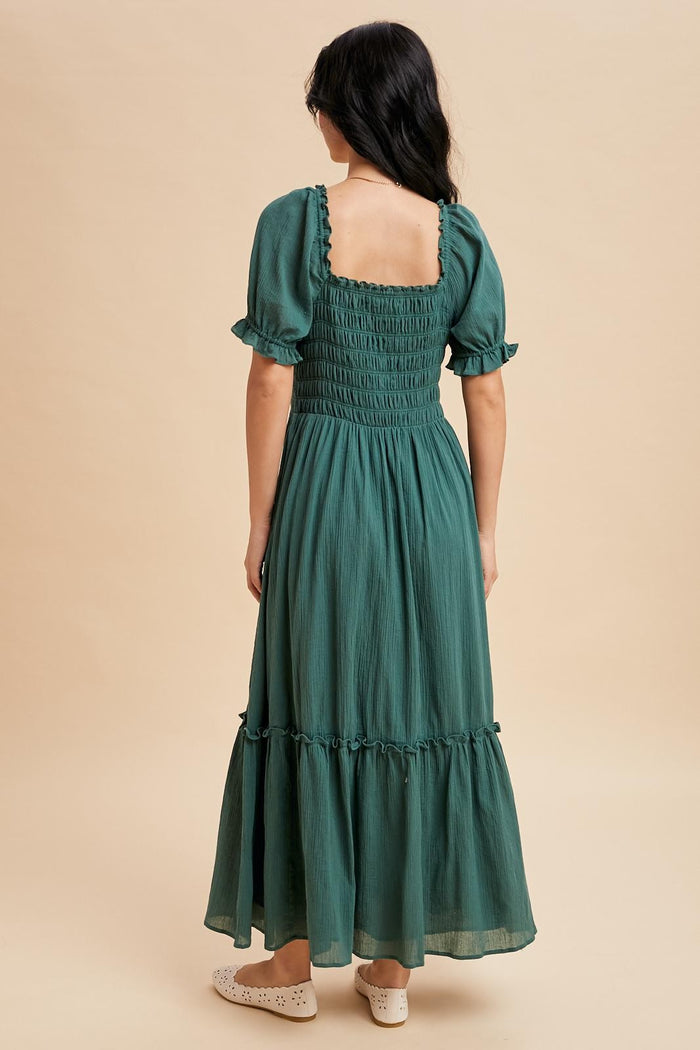 woman wearing a green smocked back maxi dress with puff sleeves and a tiered skirt