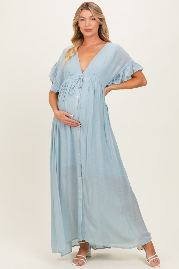 woman wearing a light blue maternity maxi dress with ruffled sleeves and a button-down front, gently holding her baby bump