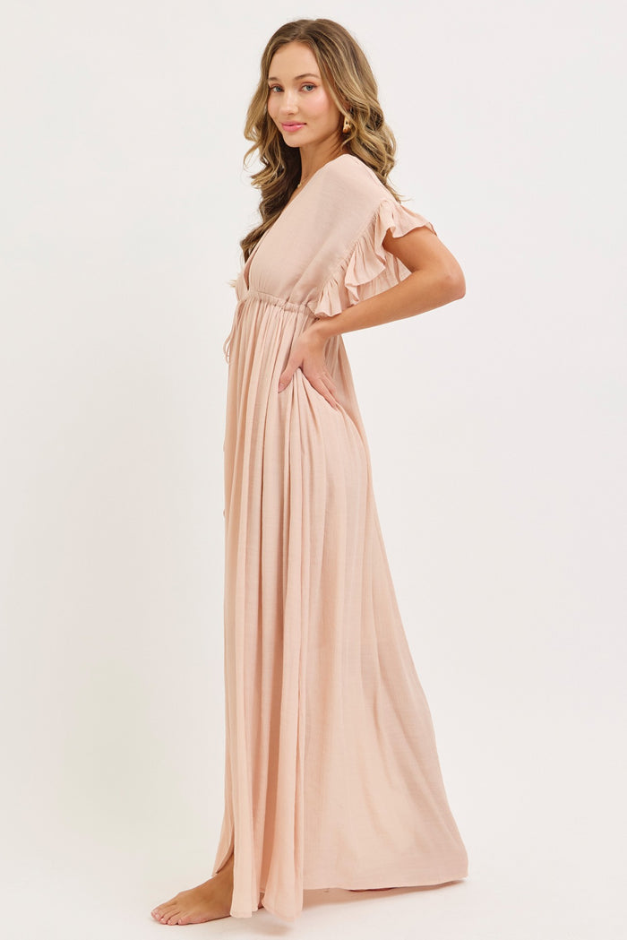 woman wearing a light pink maxi dress with ruffles on the sleeves and a cinched waist