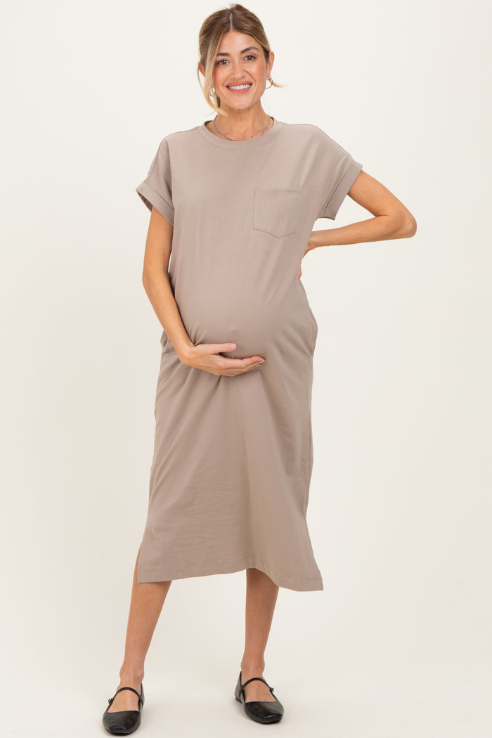 woman wearing a taupe maternity dress with short sleeves and a pocket, holding her baby bump