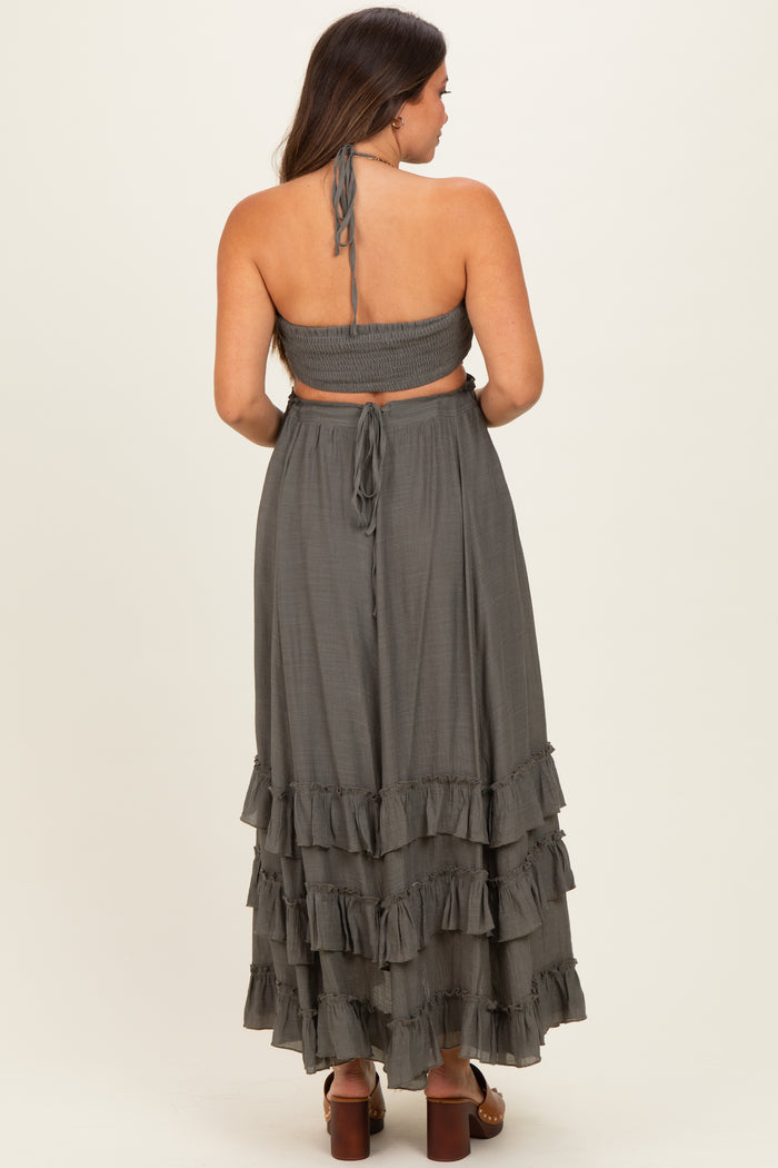 woman wearing a dark gray maternity skirt with ruffles and a matching crop top, showing a baby bump from the back
