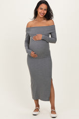 woman wearing a grey off-the-shoulder maternity dress with long sleeves and a side slit, holding her baby bump
