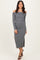 woman wearing a grey off-shoulder long sleeve midi dress with a side slit and strappy heels