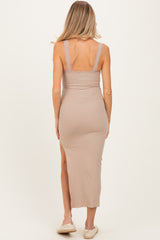 woman wearing a beige ribbed maternity dress with lace straps and a side slit, showing her back