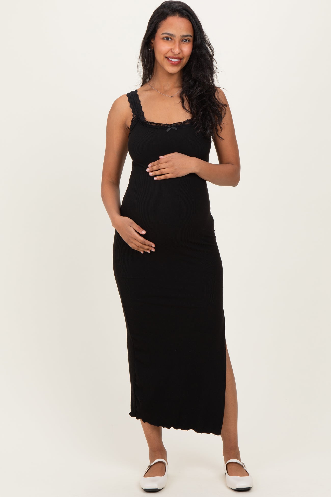 woman wearing a black maternity maxi dress with lace details and holding her baby bump