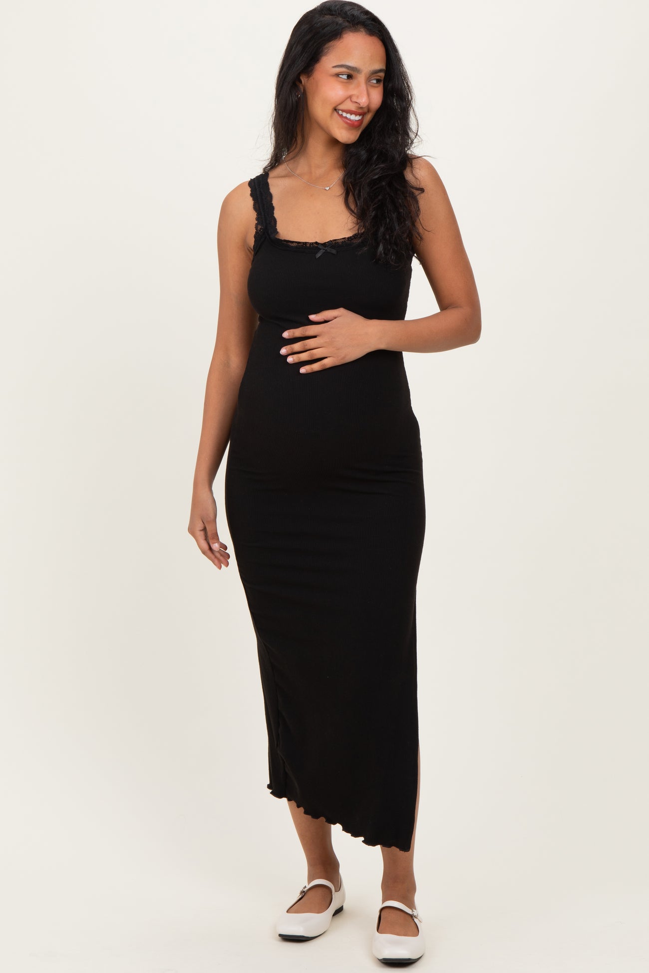 woman wearing a black maternity maxi dress with lace details and cradling her baby bump