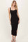 woman wearing a black sleeveless midi dress with lace trim and side slits, styled with flat sandals