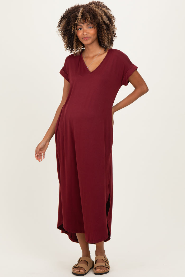 woman wearing a burgundy maternity maxi dress with short sleeves and a v-neck, showing her baby bump