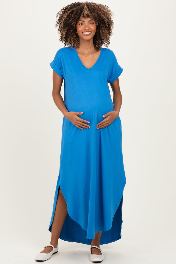 woman wearing a bright blue maternity maxi dress with a v-neck and side slits, showing her baby bump