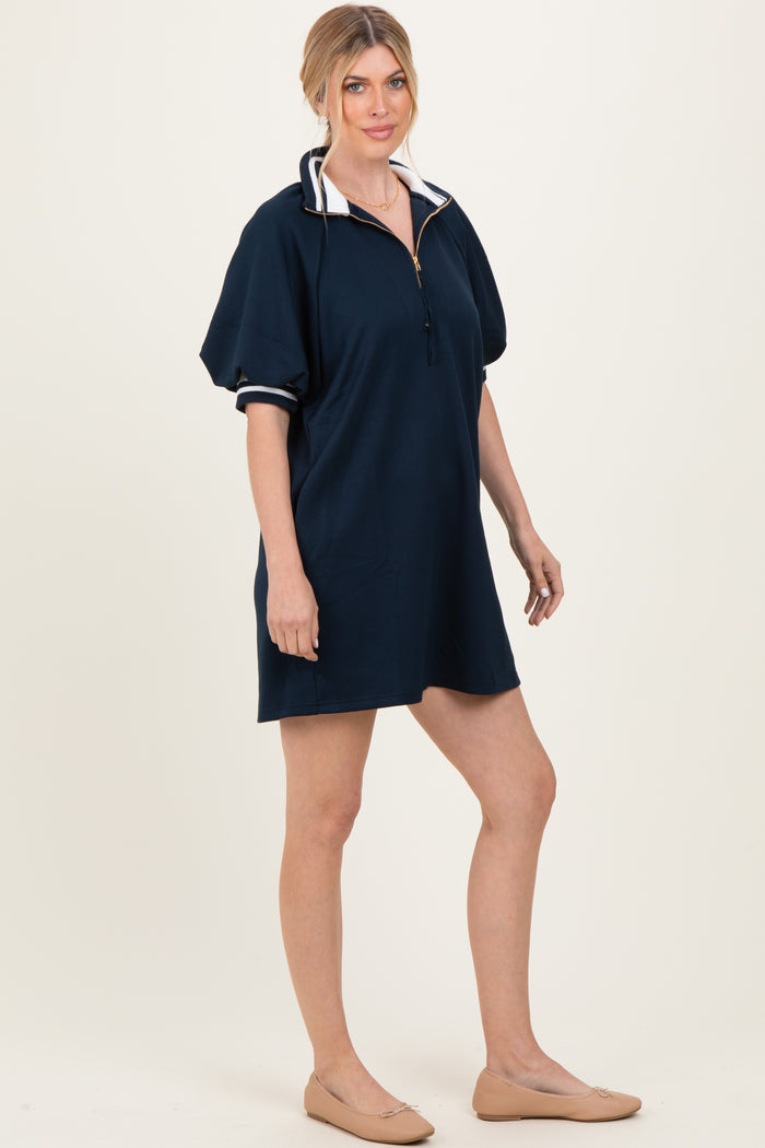woman wearing a navy blue short sleeve pullover dress with a half zipper and contrasting collar